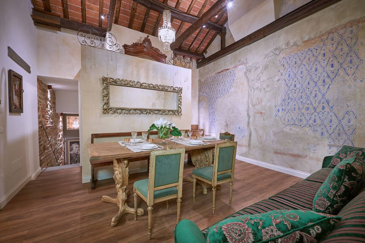 A dining area with a wooden table, green upholstered chairs, and a chandelier.