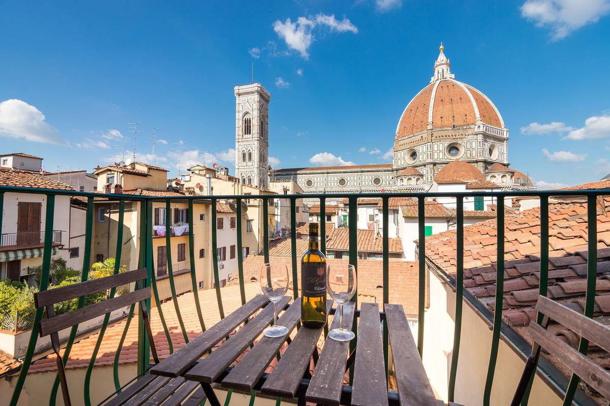 A balcony with a view of a historic building with a dome and bell tower, surrounded by traditional buildings.