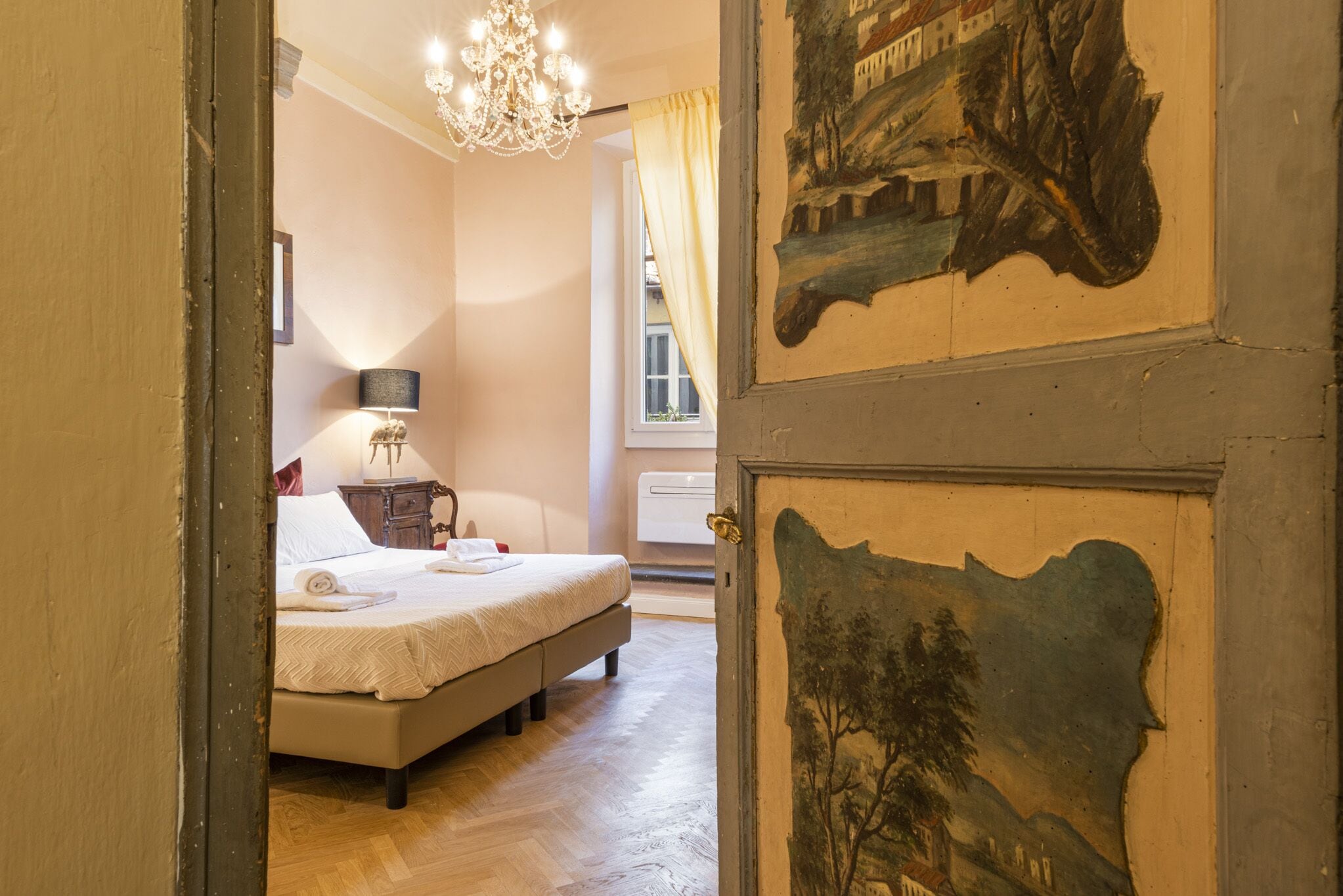 Un dormitorio con cama, mesita de noche, lámpara y ventana con cortinas.