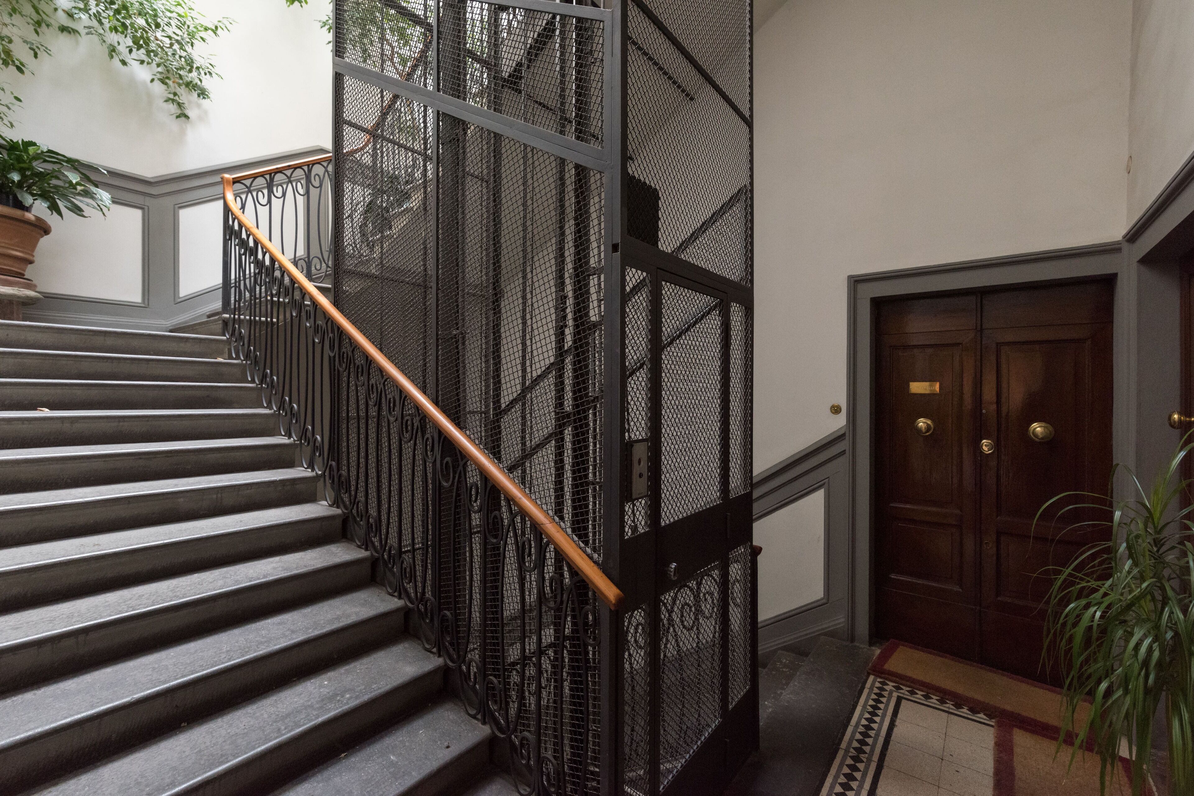 Eine Treppe mit Metallgeländer und Holzhandlauf, die zu einer Tür mit Messingklinke führt.