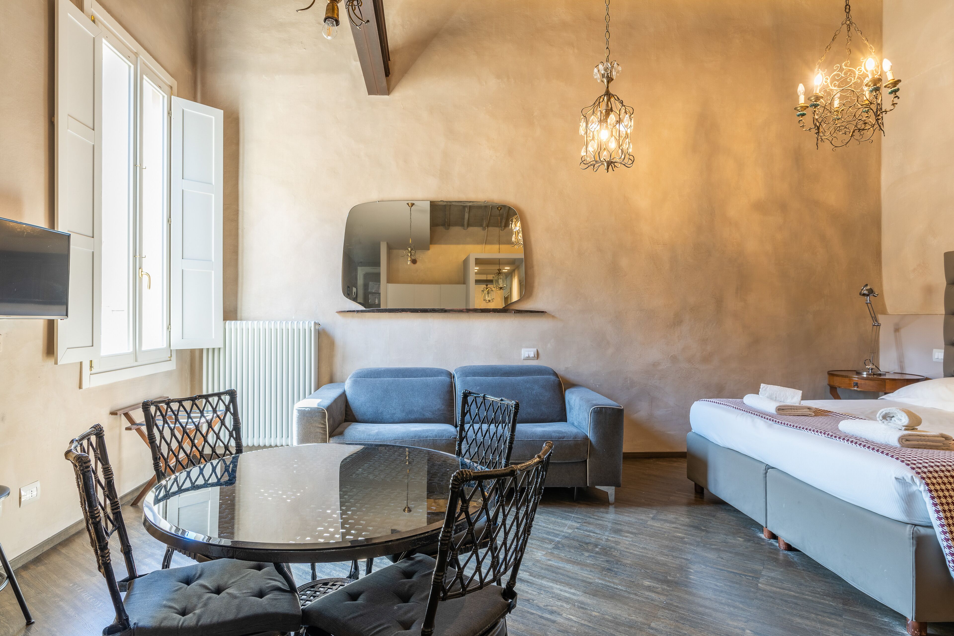 Un soggiorno moderno con un tavolo da pranzo in vetro, due divani, un grande specchio e un lampadario.