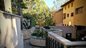 Une cour avec un chemin en pierre, un petit jardin et des bâtiments dotés de balcons.