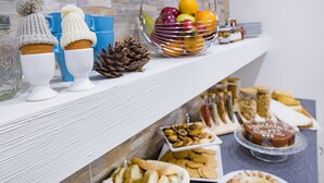 Une table de buffet proposant une variété d’aliments, notamment des fruits, des pâtisseries et du pain.