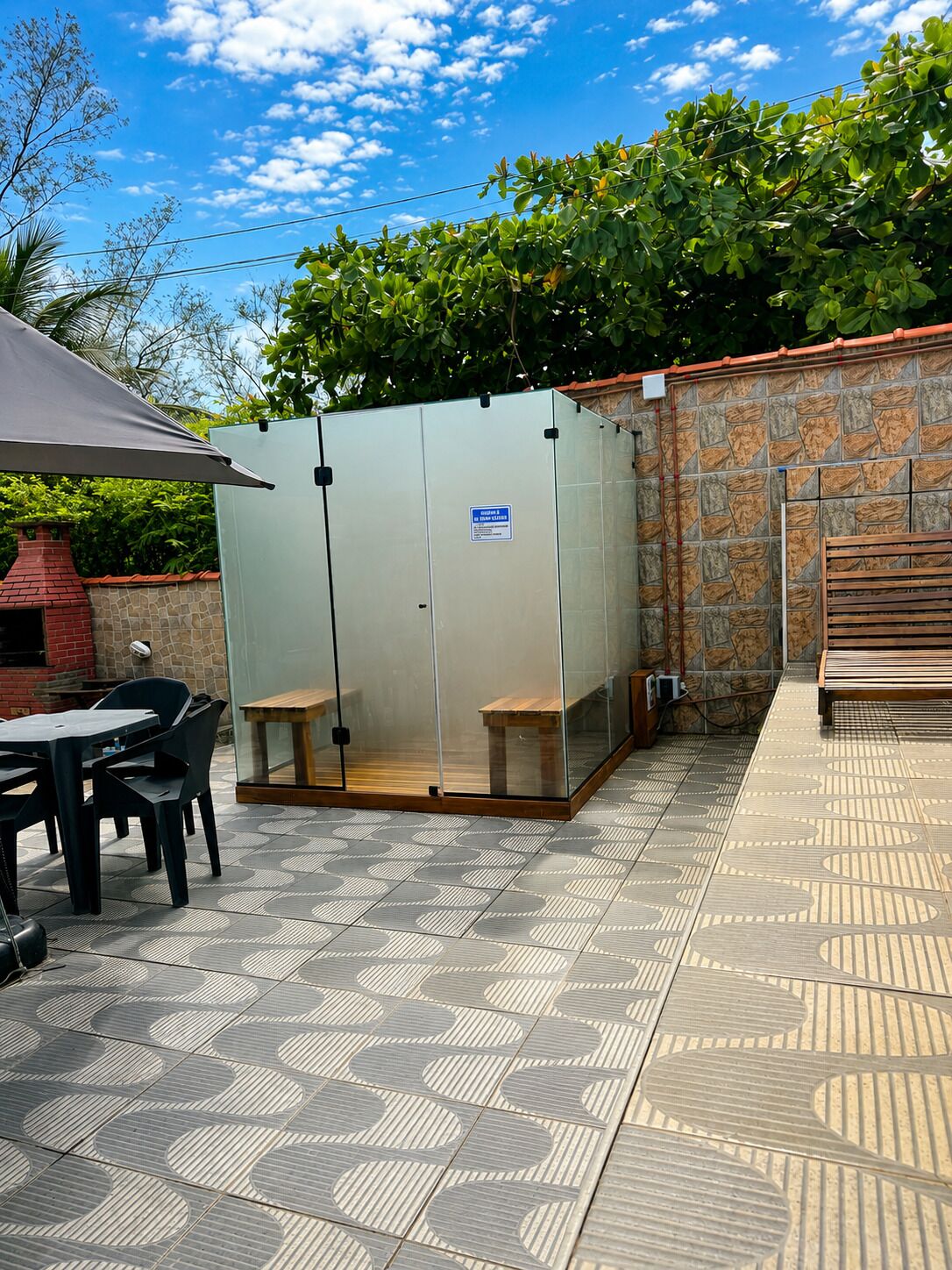 A patio area with a covered seating area, a stone wall, and a tiled floor.