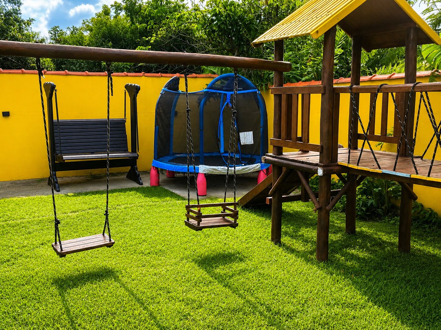 A playground with swings, a trampoline, and a small wooden structure.