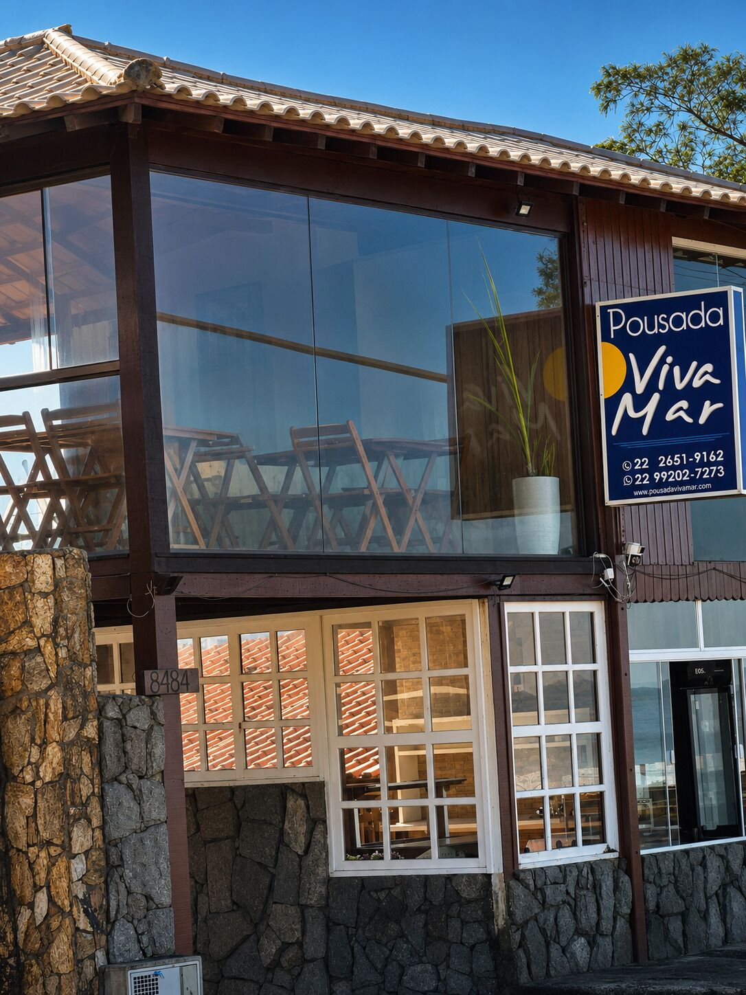 En toetagers bygning med store vinduer, en stenfassade og et skilt der reklamerer for 'Pousada Viva Mar'.