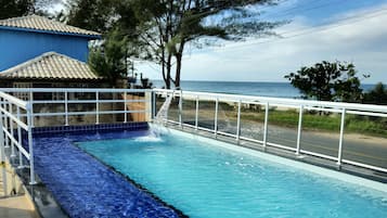 Una piscina al aire libre, sombrillas, sillones reclinables de piscina