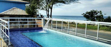 Una piscina al aire libre, sombrillas, sillones reclinables de piscina