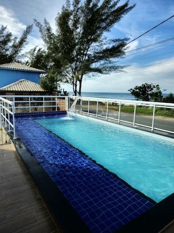 Una piscina al aire libre, sombrillas, sillones reclinables de piscina