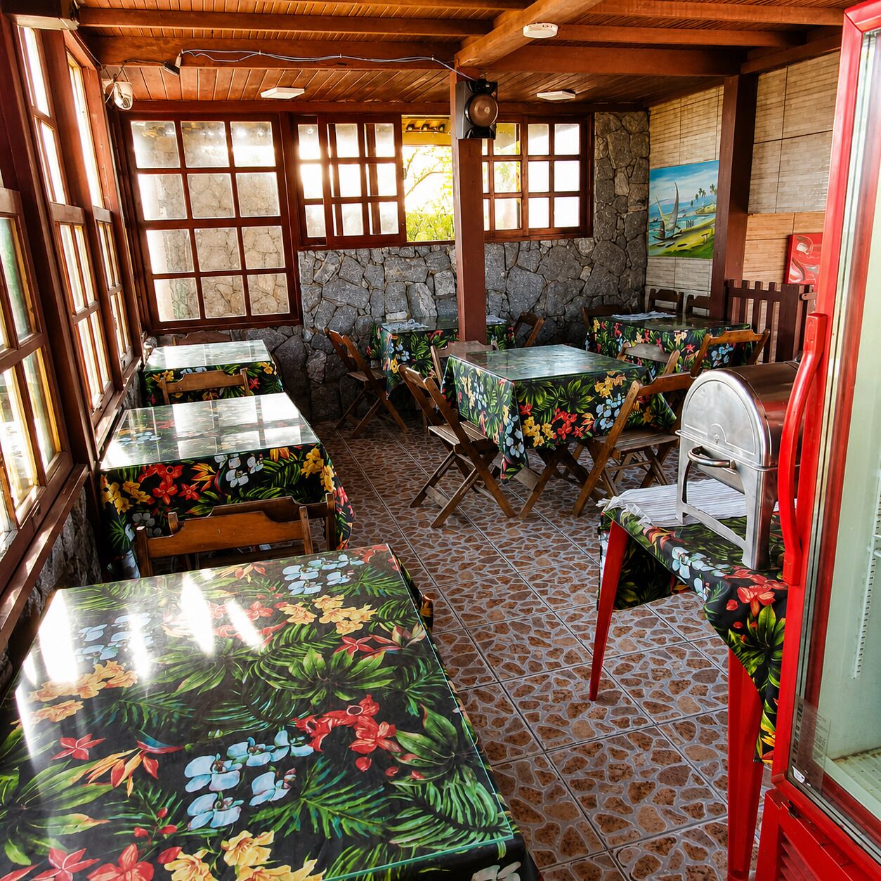 Un restaurant avec des tables et des chaises en bois, des murs en pierre et de grandes fenêtres.
