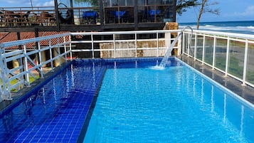 Una piscina al aire libre, sombrillas, sillones reclinables de piscina