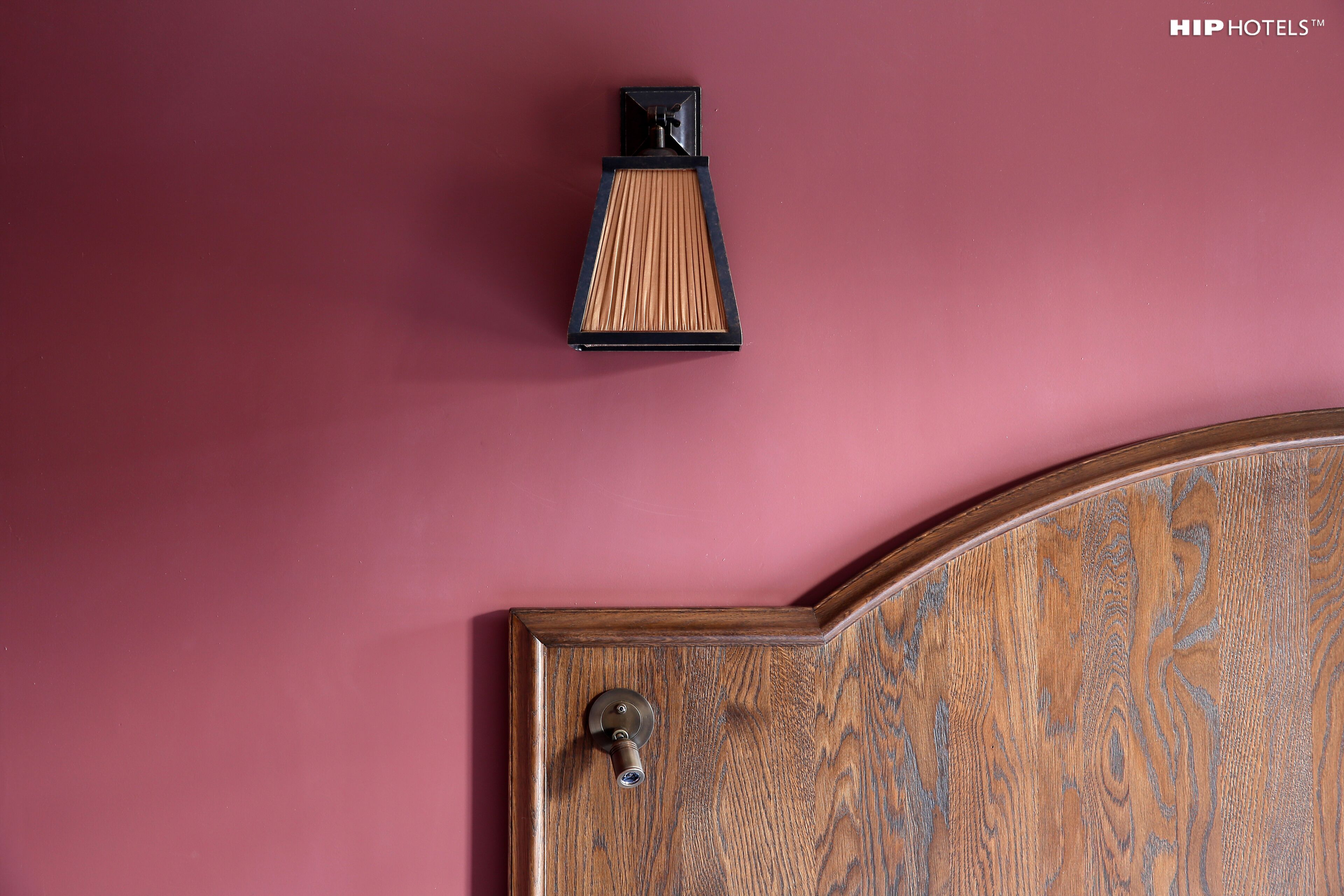 A wooden door with a brass doorknob and a keyhole, set against a maroon wall.