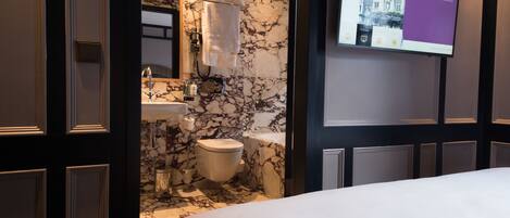 A modern bathroom with a marble backsplash, a sink, a toilet, and a large mirror.
