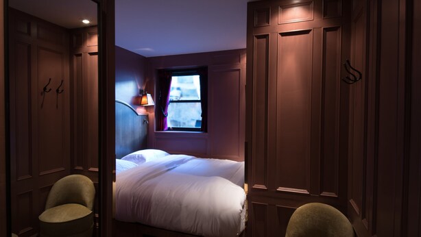 A bedroom with a single bed, a window with curtains, a nightstand, and two chairs. - Mimi's Hotel Soho (London)