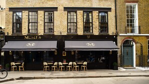 A hotel with a black awning, outdoor seating area, and a bicycle parked outside. - Mimi's Hotel Soho (London)