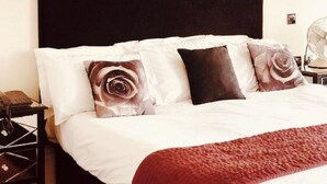 Een slaapkamer met een groot bed, een donker hoofdbord en decoratieve kussens.