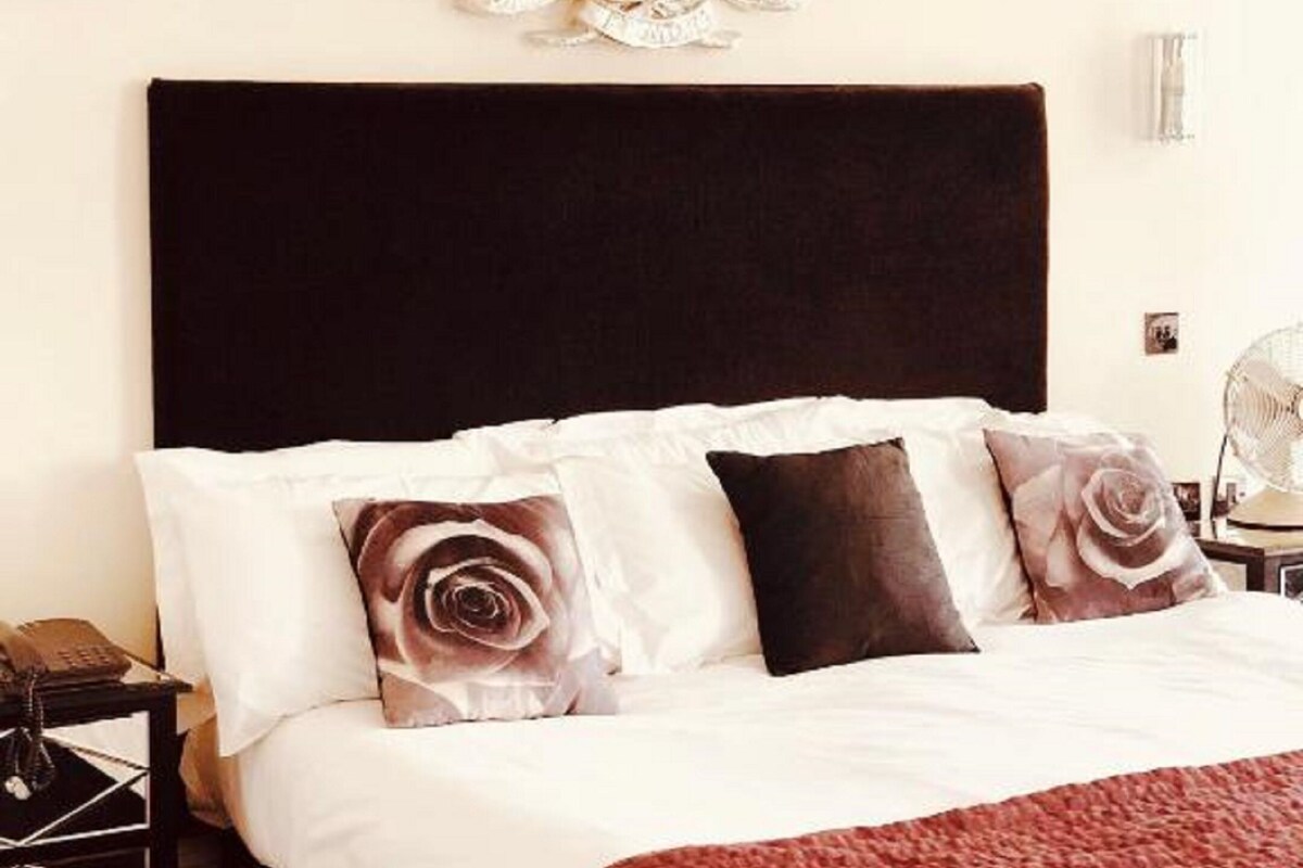 Une chambre à coucher avec un grand lit, une tête de lit sombre et des coussins décoratifs.