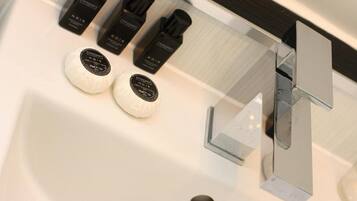 Une salle de bain moderne avec un lavabo blanc, deux distributeurs de savon ronds et un robinet chromé.