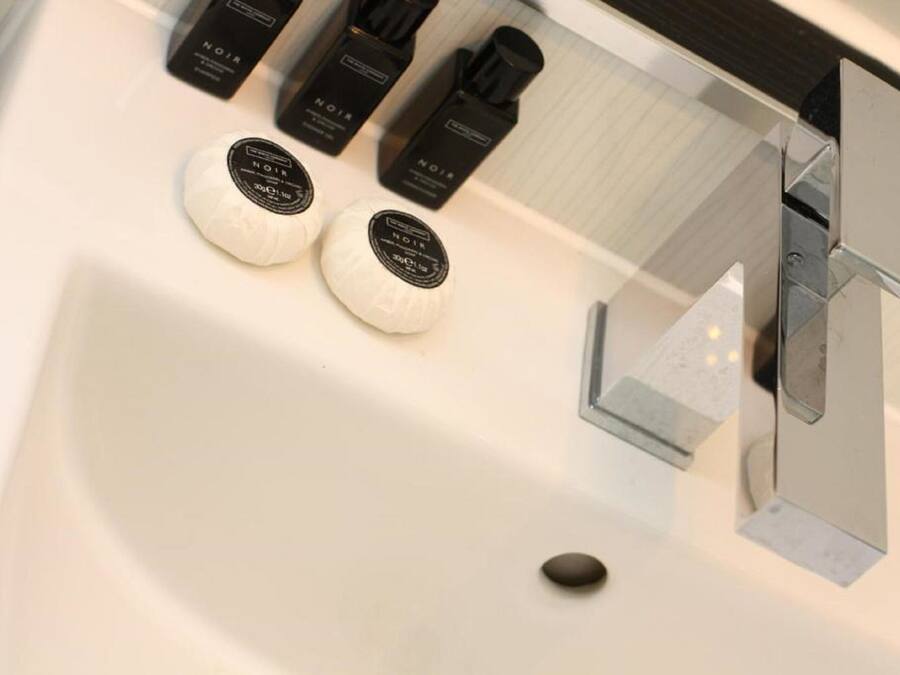 Une salle de bain moderne avec un lavabo blanc, deux distributeurs de savon ronds et un robinet chromé.