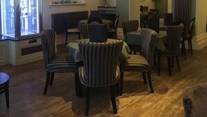 Een eetgedeelte met gestreepte stoelen, een centrale tafel en een raam met jaloezieën.
