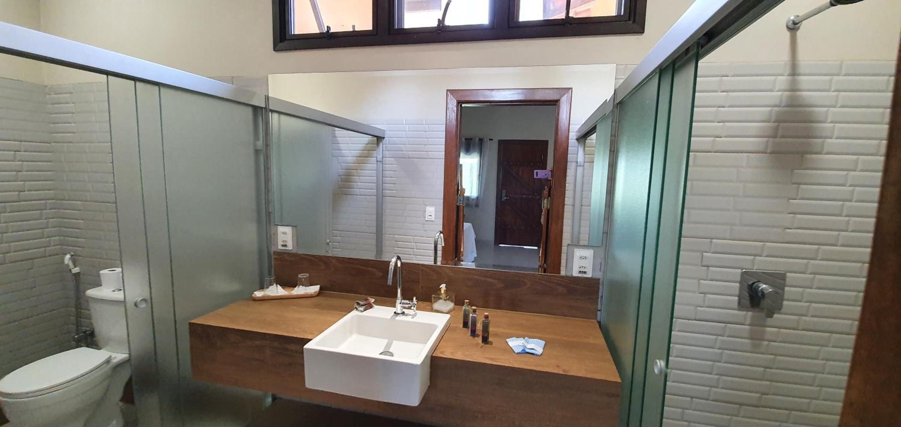 A bathroom with a wooden vanity, a white sink, and a large mirror.