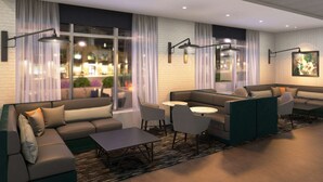 A modern lounge area with a sectional sofa, a small round table, and two armchairs. There are two pendant lights above the seating area. - Hyatt Place Austin Airport (Austin)