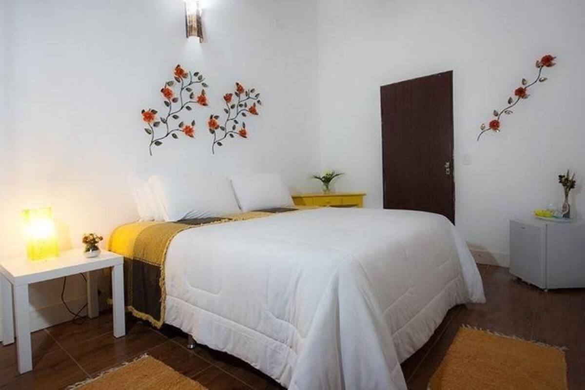 A bedroom with a bed, a bedside table, a nightstand, and wall decorations.