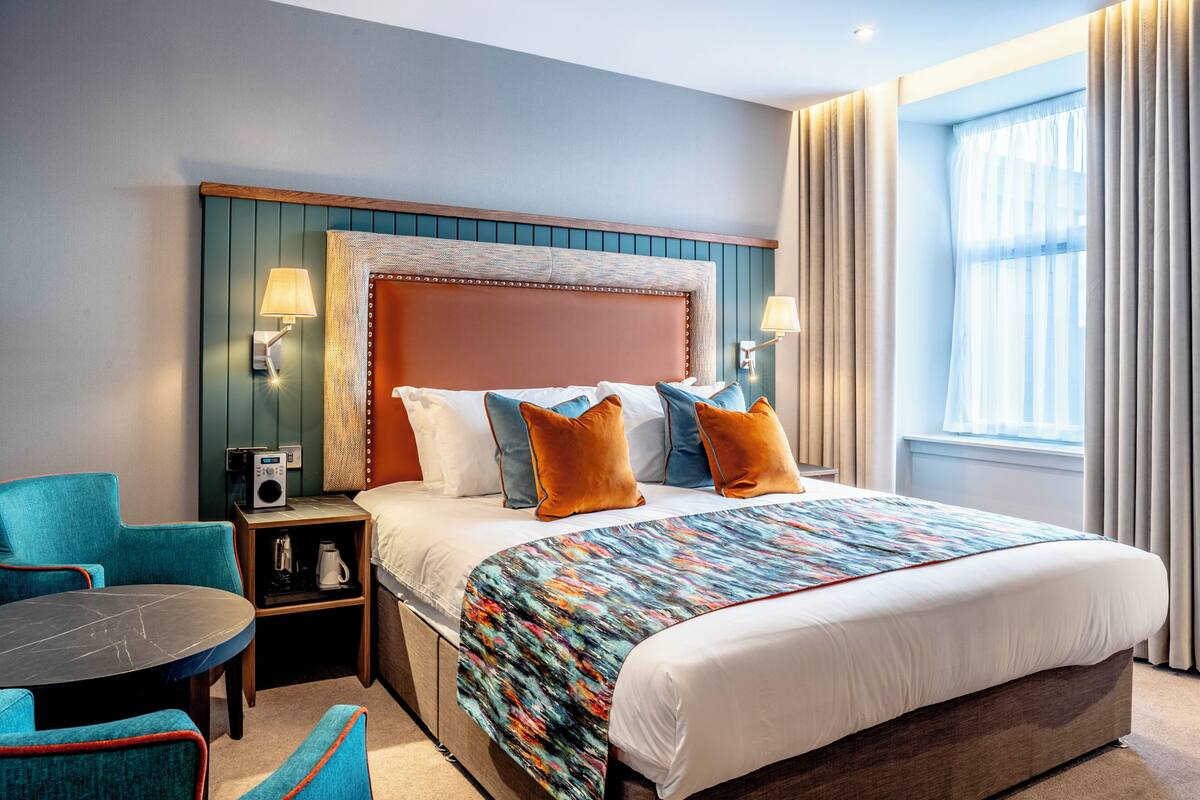 A hotel room with a bed, two nightstands, a table, and two chairs.