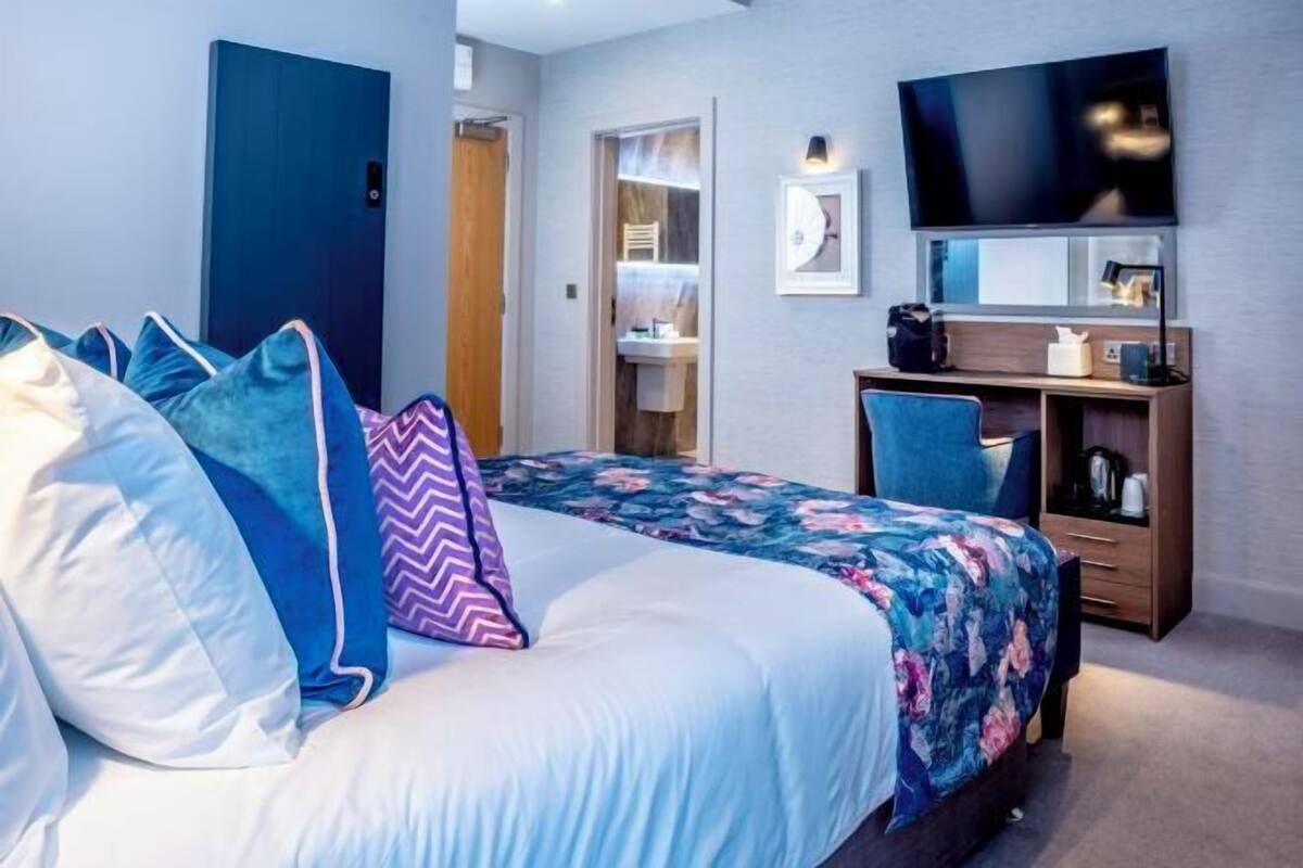 A bedroom with a bed, a desk, a television, and a wardrobe.