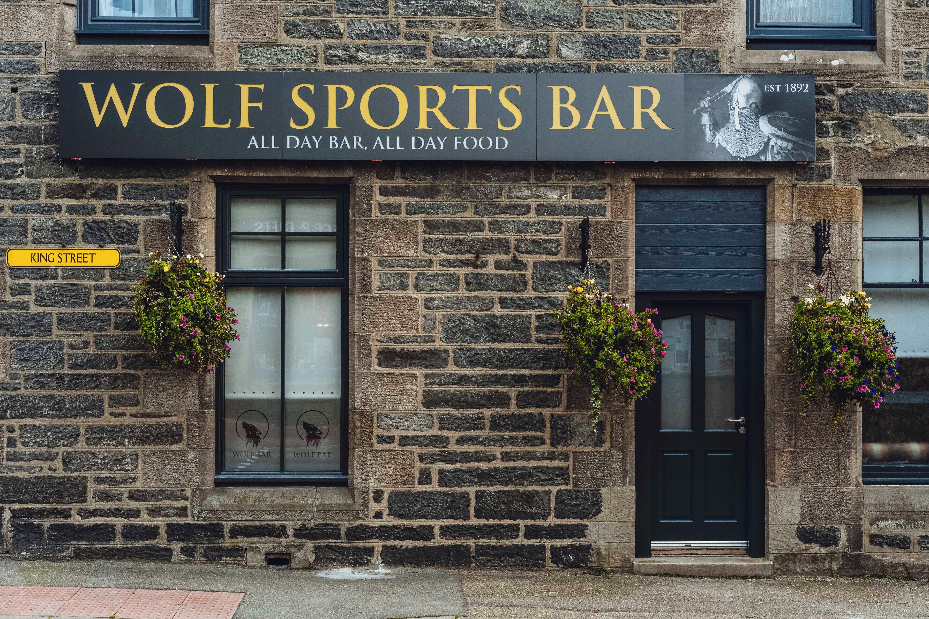 A building with a sign reading "WOLF SPORTS BAR" and "EST 1892".