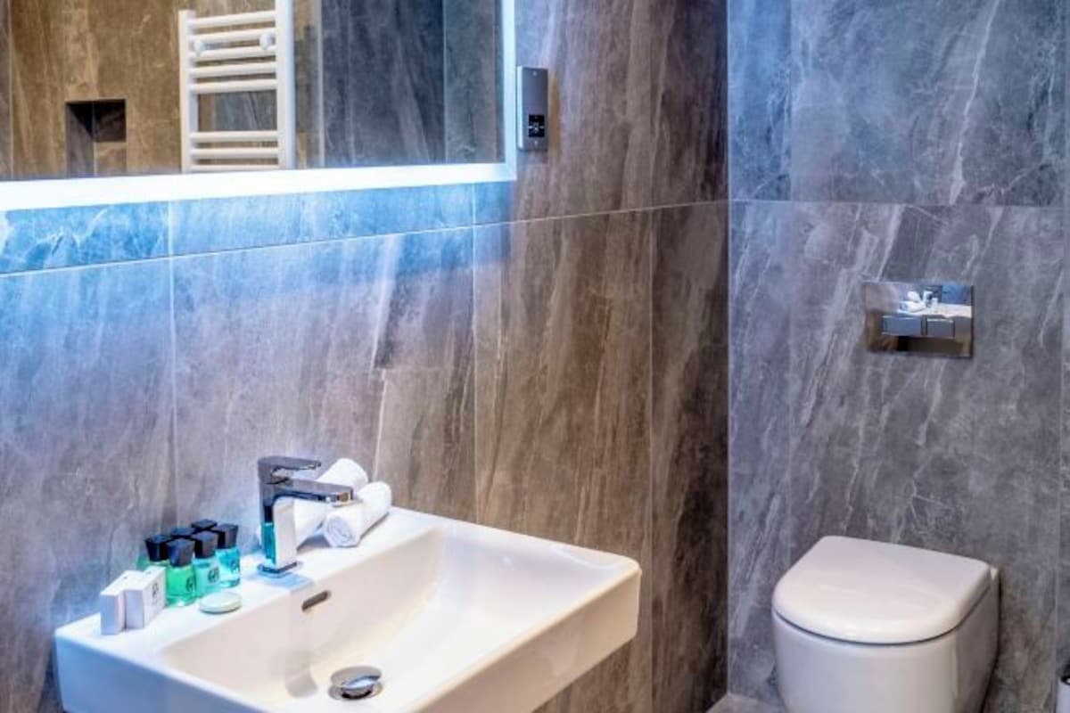 A bathroom with a white sink, mirror, and toilet.