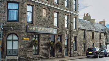 A stone building with a sign reading "WOLF SPORTS BAR".