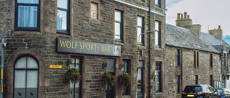 A stone building with a sign reading "WOLF SPORTS BAR".