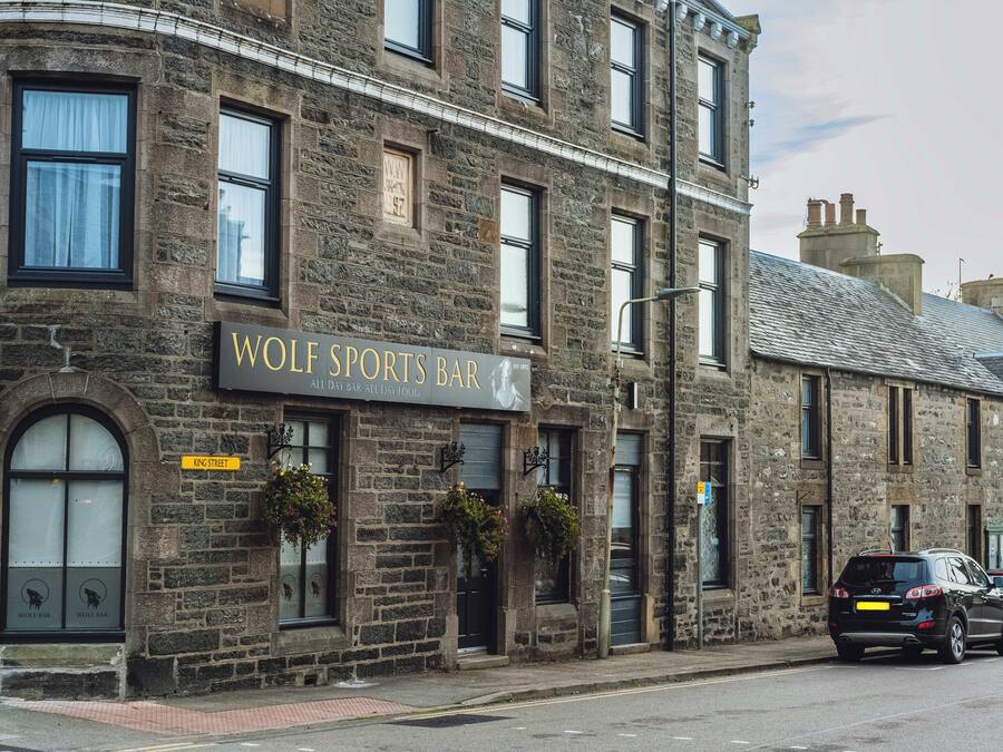 A stone building with a sign reading "WOLF SPORTS BAR".