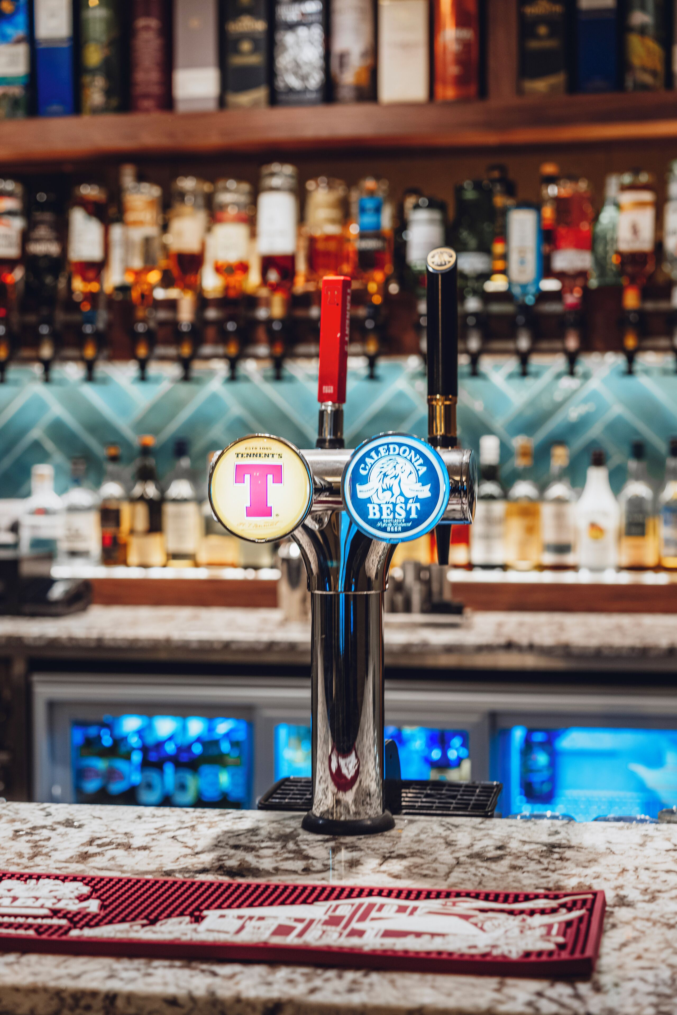 Un robinet de bar avec deux tireuses à bière, l’une portant l’inscription « T » et l’autre « GALEDONIA BEST ».