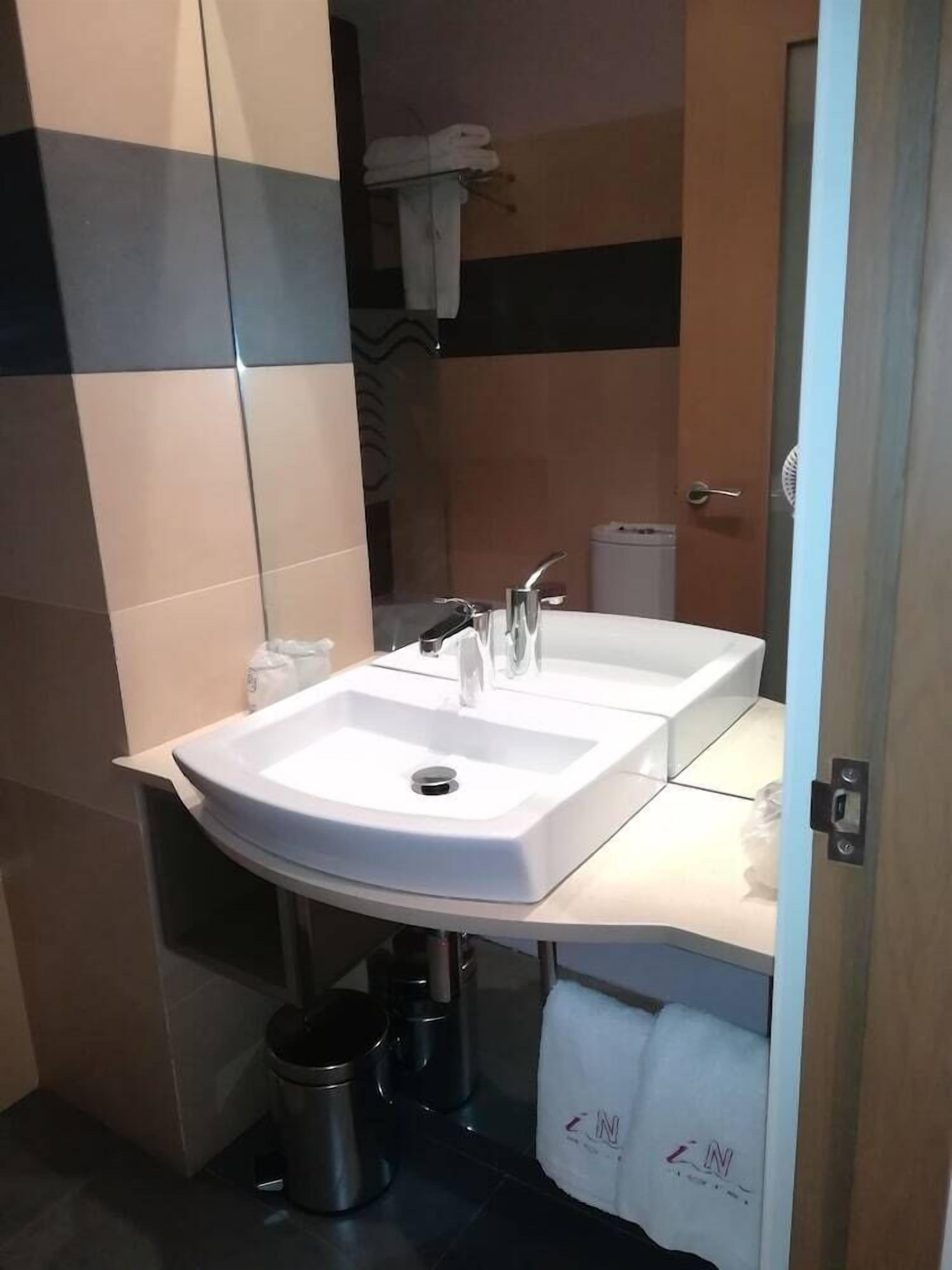 Een badkamer met twee wastafels, een spiegel, een handdoekhouder en een vuilnisbak.