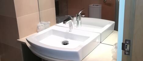 Un baño moderno con dos lavamanos, un inodoro y un cubo de basura.