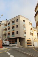 Un edificio de varios pisos con fachada plana, balcones y una entrada visible.