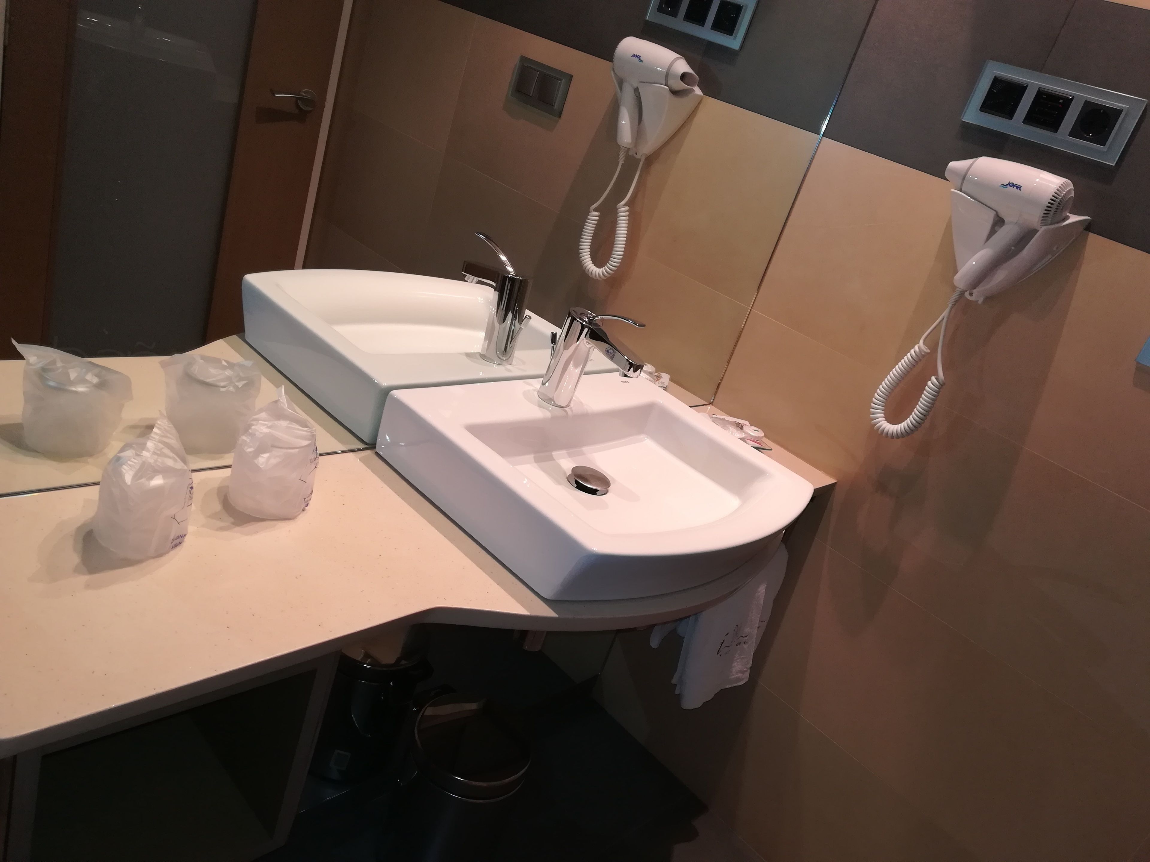 A bathroom with two sinks, a mirror, and two hair dryers.