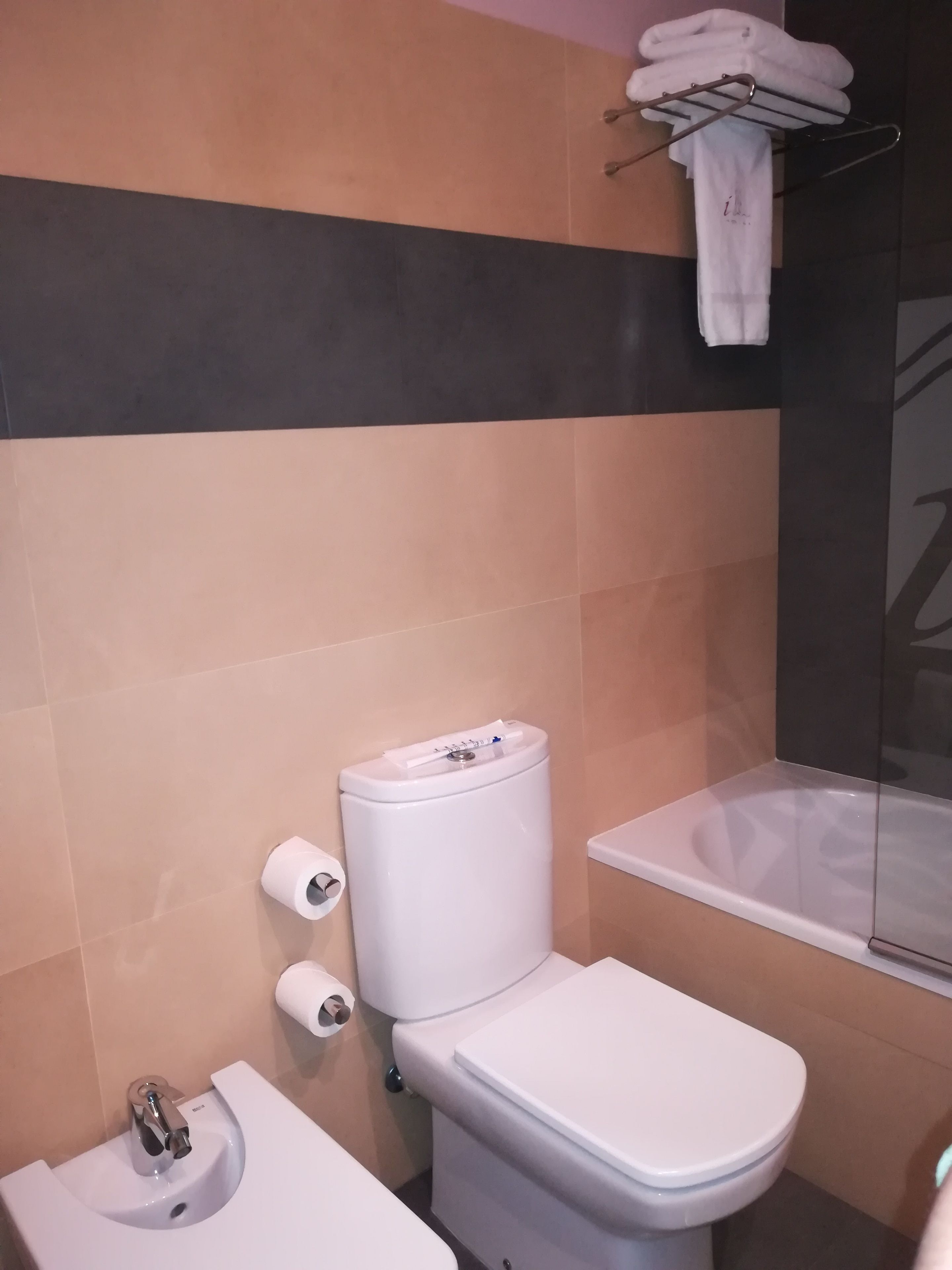 A bathroom with a toilet, bidet, and a towel rack.