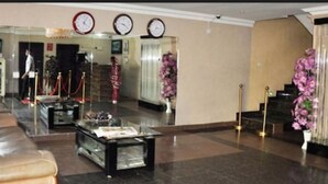 A lobby with a sofa, a coffee table, a reception desk, and a staircase. - Keviz Hotel (Lagos)