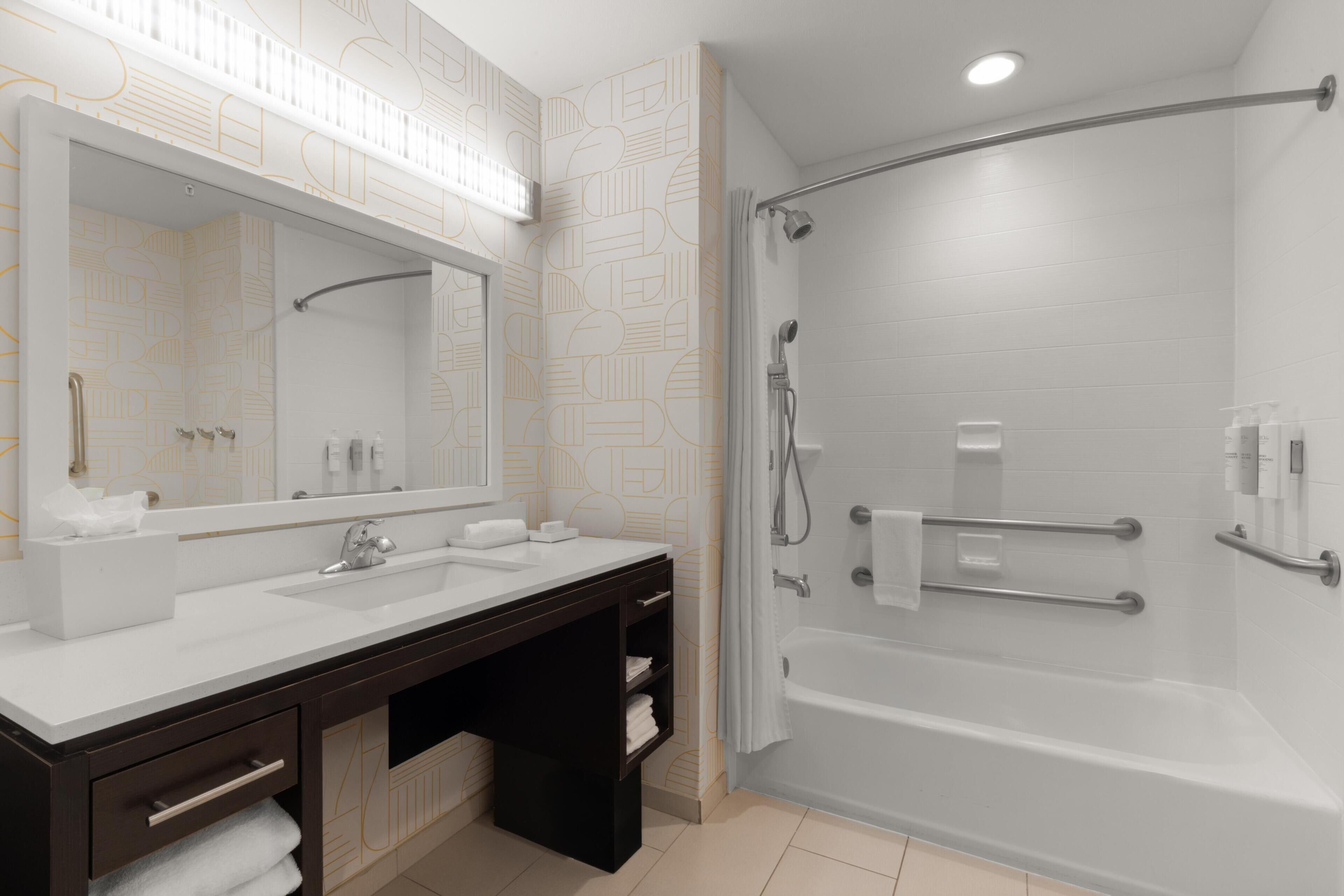 Un bagno moderno con uno specchio grande, due lavandini, una vasca e una doccia.