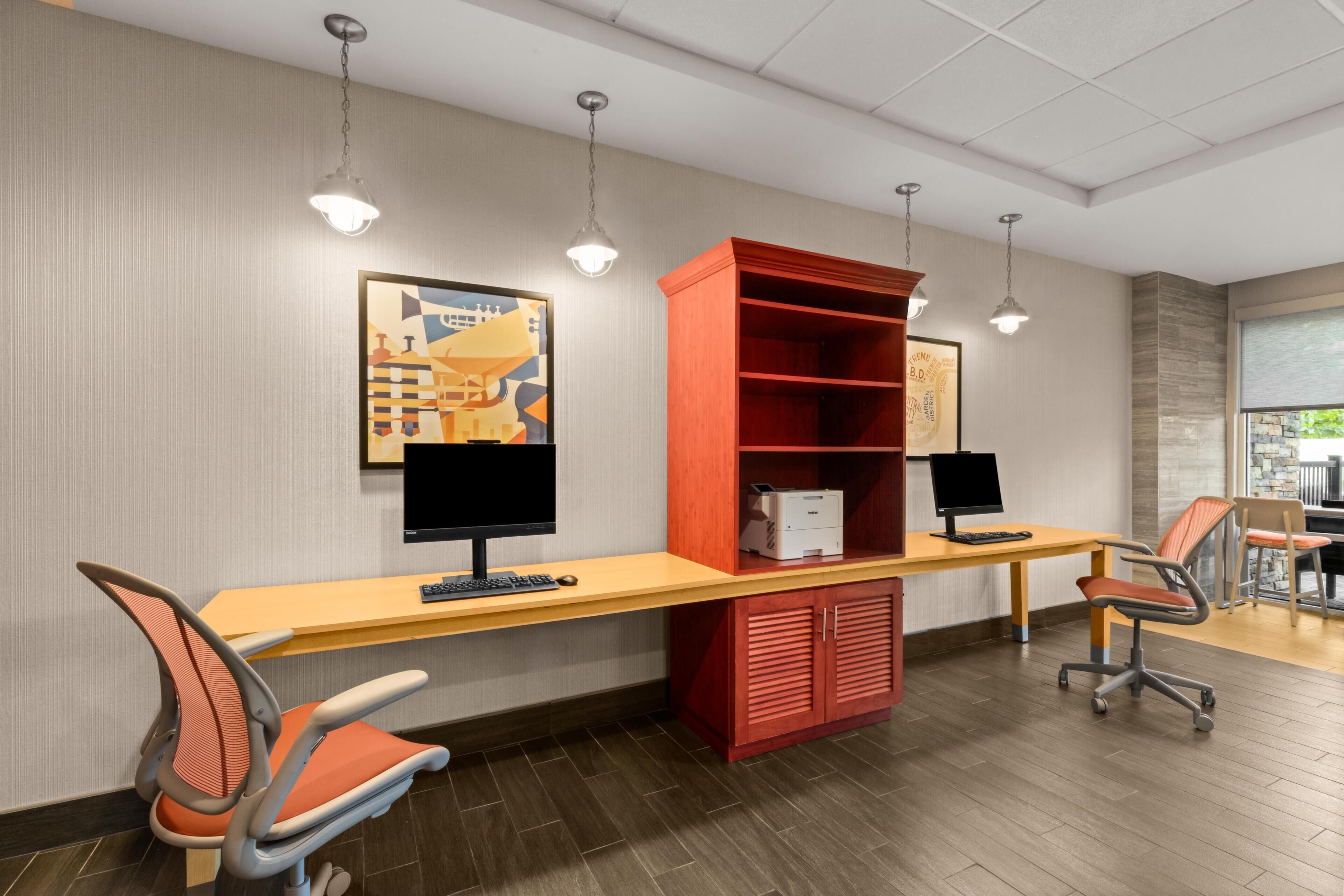 A modern office space with two desks, chairs, a bookshelf, and artwork on the wall.