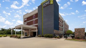 Un hôtel reconnaissable à son grand panneau « HOME 2 », à son entrée abritée et à son espace de stationnement.