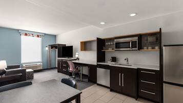 A modern kitchen with a dining area, built-in appliances, and a flat-screen TV.