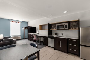 Una cocina moderna con comedor, electrodomésticos integrados y un televisor de pantalla plana.
