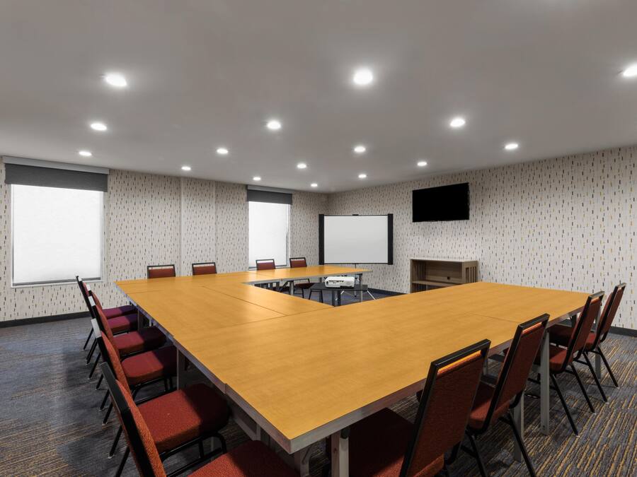 A conference room with a long table, chairs, a projector, and a screen.