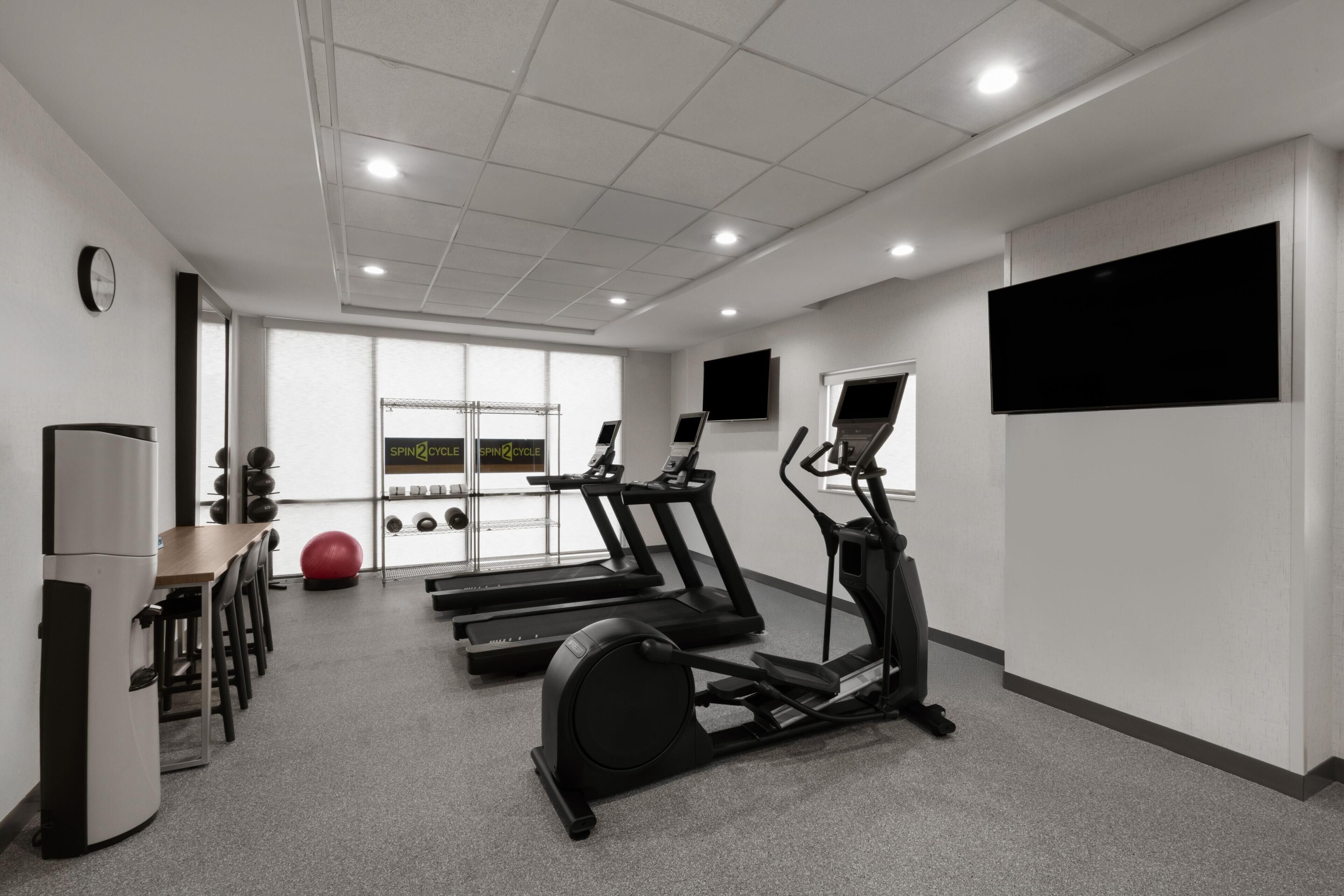 Un gimnasio con cintas de correr, una bicicleta estática y pelotas de ejercicio.