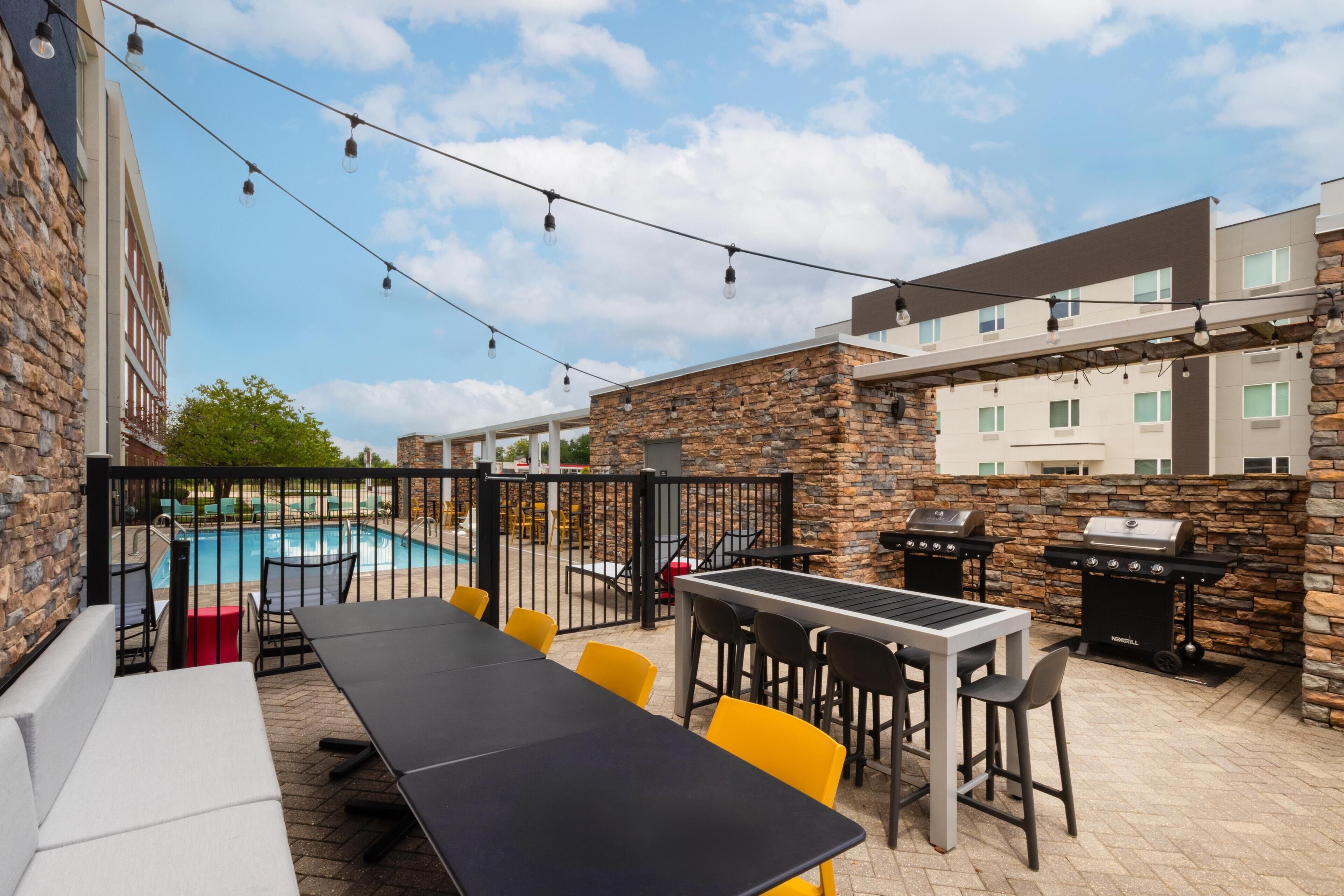 An outdoor patio area with a pool, outdoor seating, and a barbecue grill.