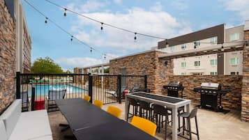 An outdoor patio area with a pool, outdoor seating, and a barbecue grill.